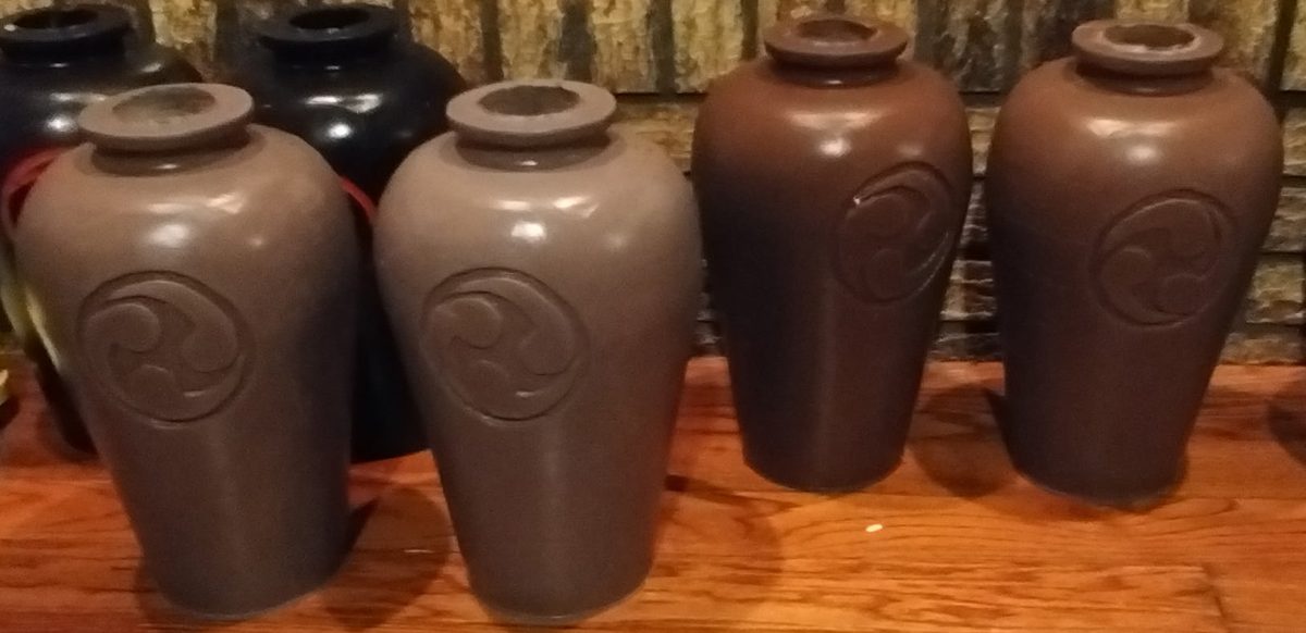 Four nigiri-game jars in gray and brown finishes with a carved crest