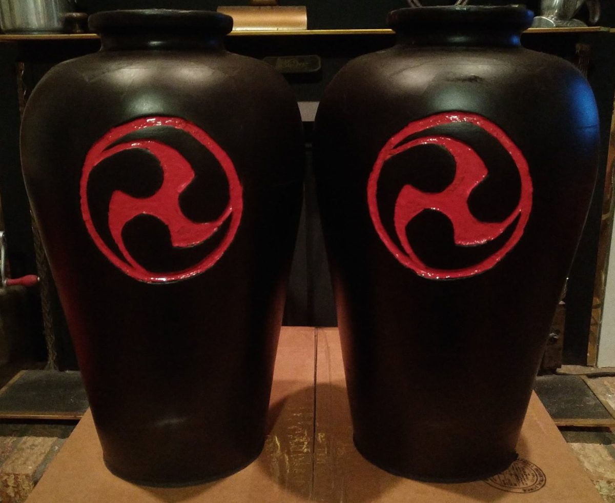 A pair of black nigiri-game jars with a red carved crest